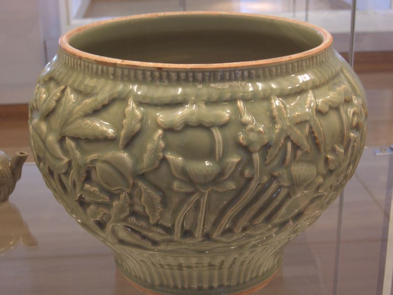 Zdjęcie przedstawiające zielone naczynie ceramiczne z wytłoczonymi wzorami kwiatowymi